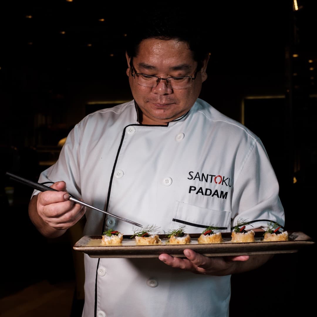 Chef Padam of Santoku plating a dish of seared bites tableside.