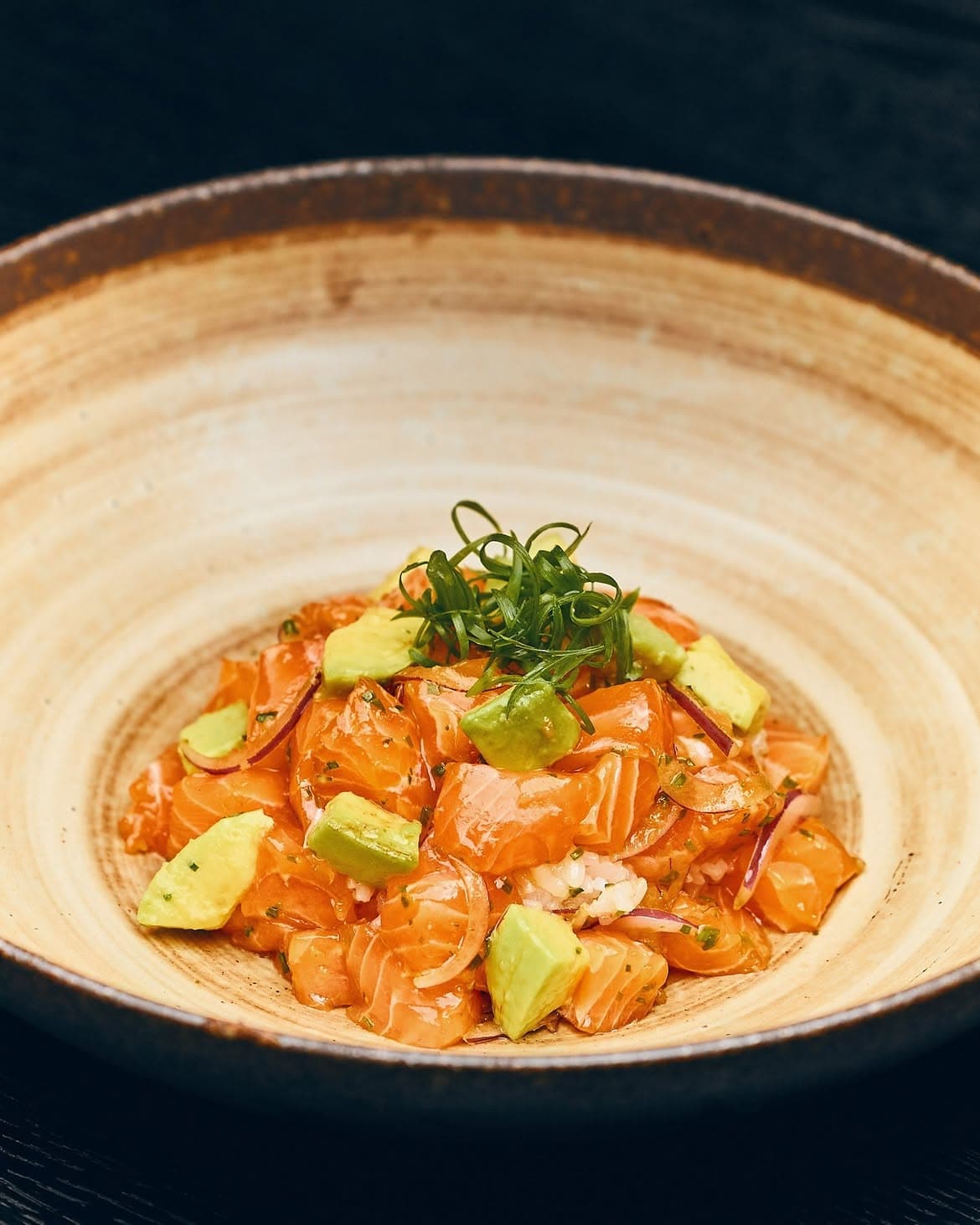 Diced salmon poke with avocado, red onion, and spring onion over sushi rice.